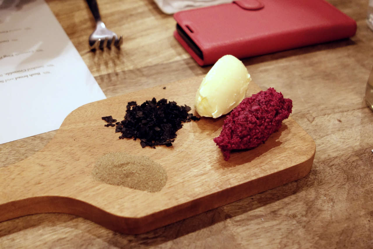 Pepperberry, beetroot butter, black salt and butter on a wooden paddle