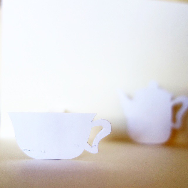 10: Paper cutout of teacup with blurry paper cutout of teapot in background