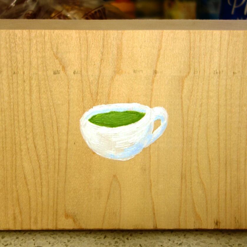 100: Painting of a white teacup full of green matcha tea, acrylic on pine board