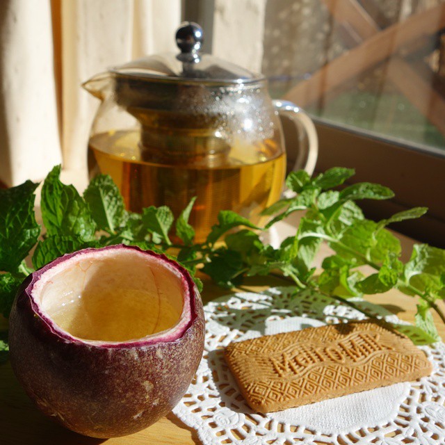12: A simple teacup fashioned from a passionfruit rind, photographed next to a biscuit, teapot and mint sprig