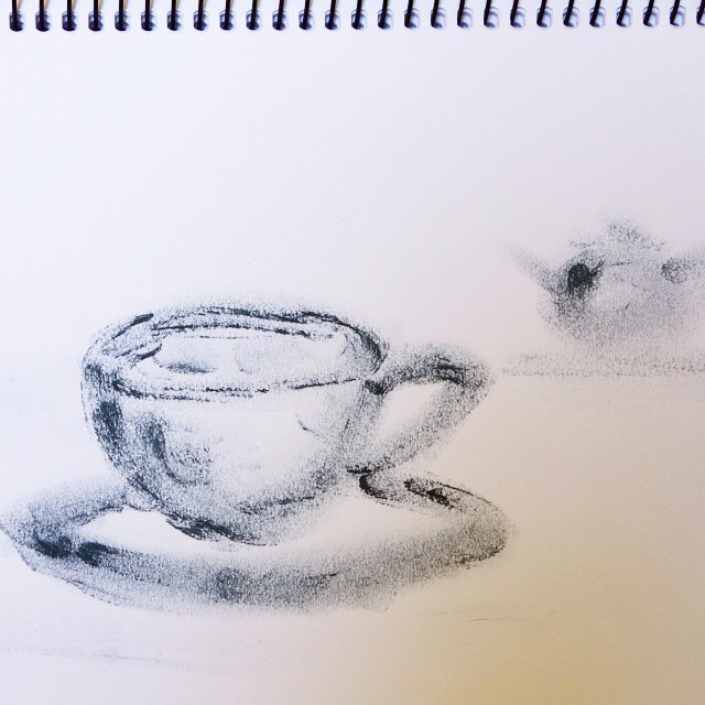 17: Black ink fingerpainted outline of a teacup with blurry teapot in background