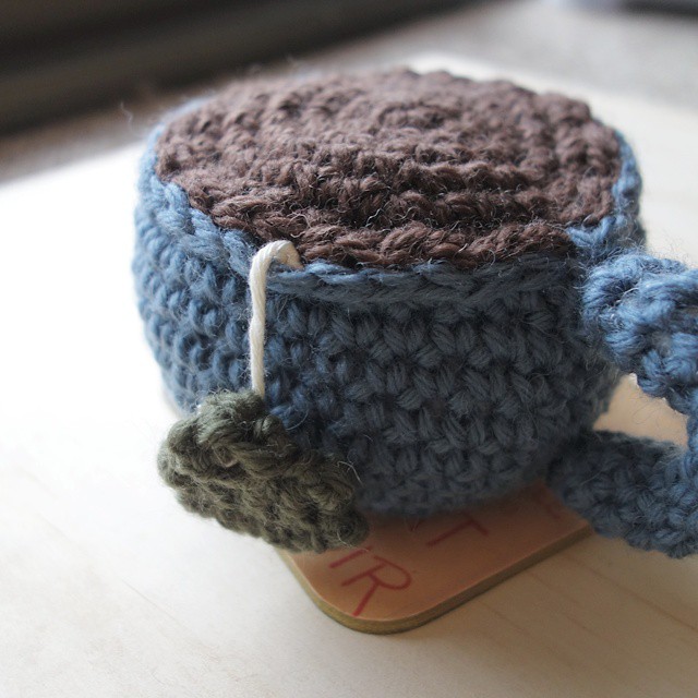 4: Blue crochet amigurumi teacup with tag hanging out