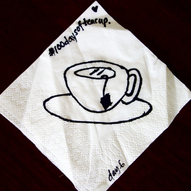 6: Black marker line drawing of a teacup on a white paper napkin